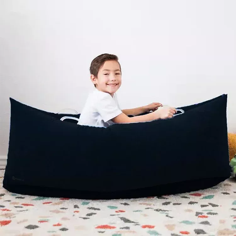 Boy is shown sitting inside black boat shaped pea pod